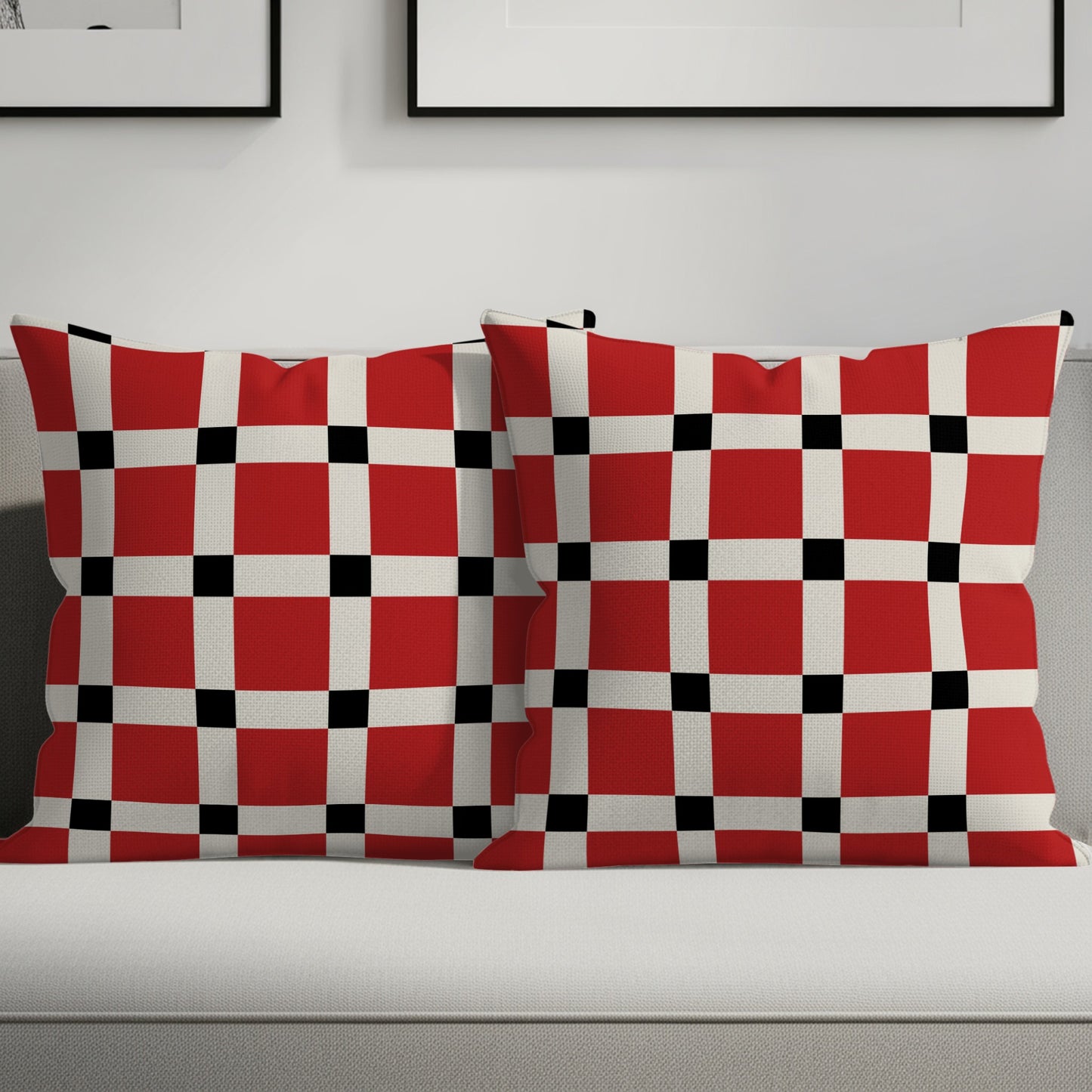 Two square throw pillows with a red, white, and black checkerboard pattern rest on a sofa.