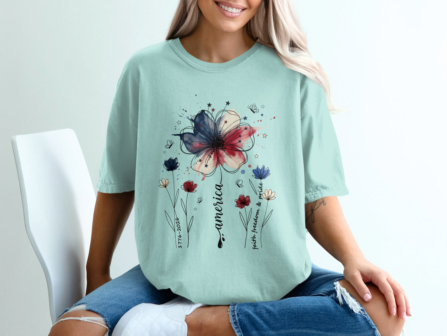 Light blue t-shirt with red, white, and blue floral design and patriotic text.