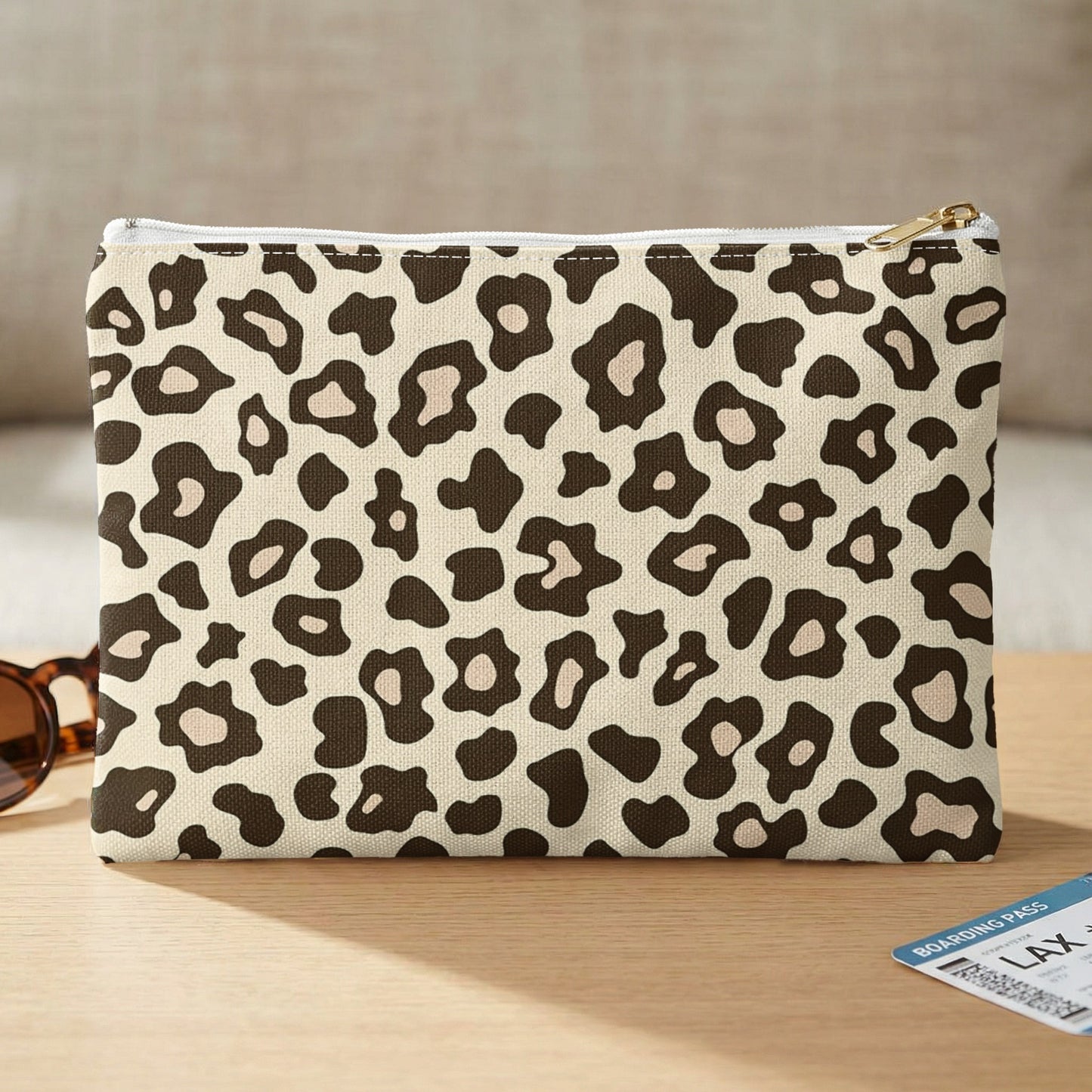 Pouch with leopard print pattern, gold zipper, and sunglasses on a table.