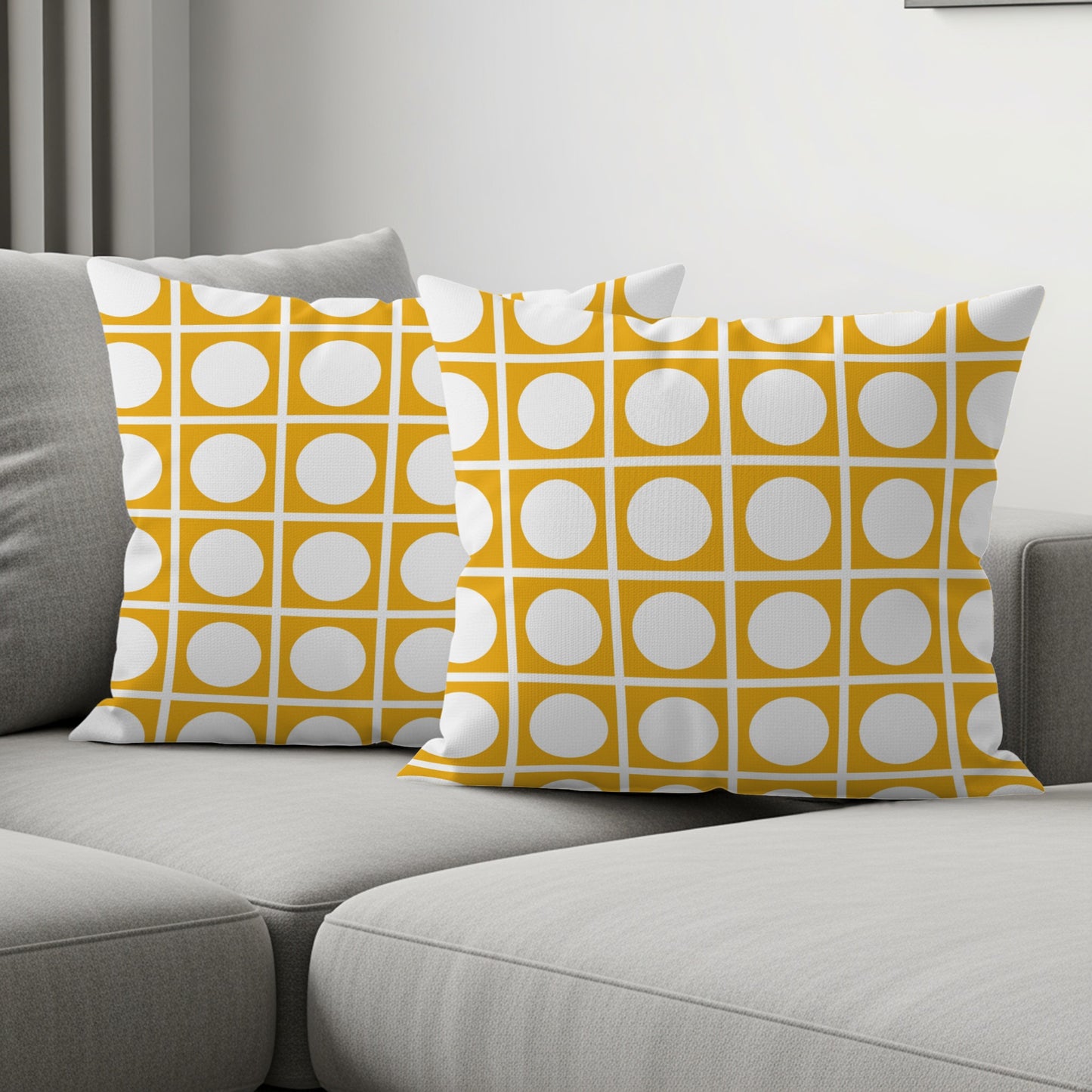 Two cushions with geometric yellow and white circle pattern on grey sofa.
