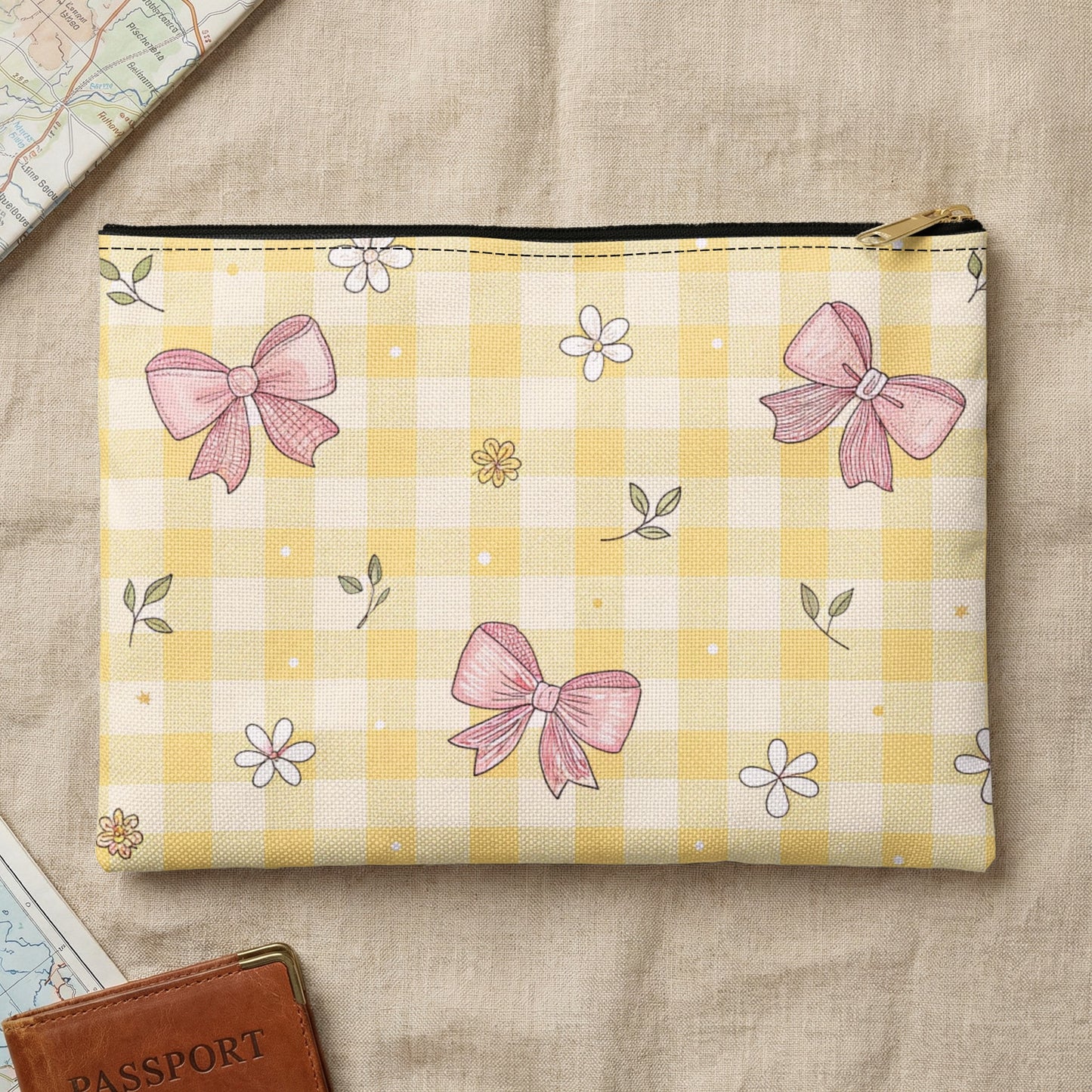 Yellow gingham pouch with pink bows and flowers on a textured surface.