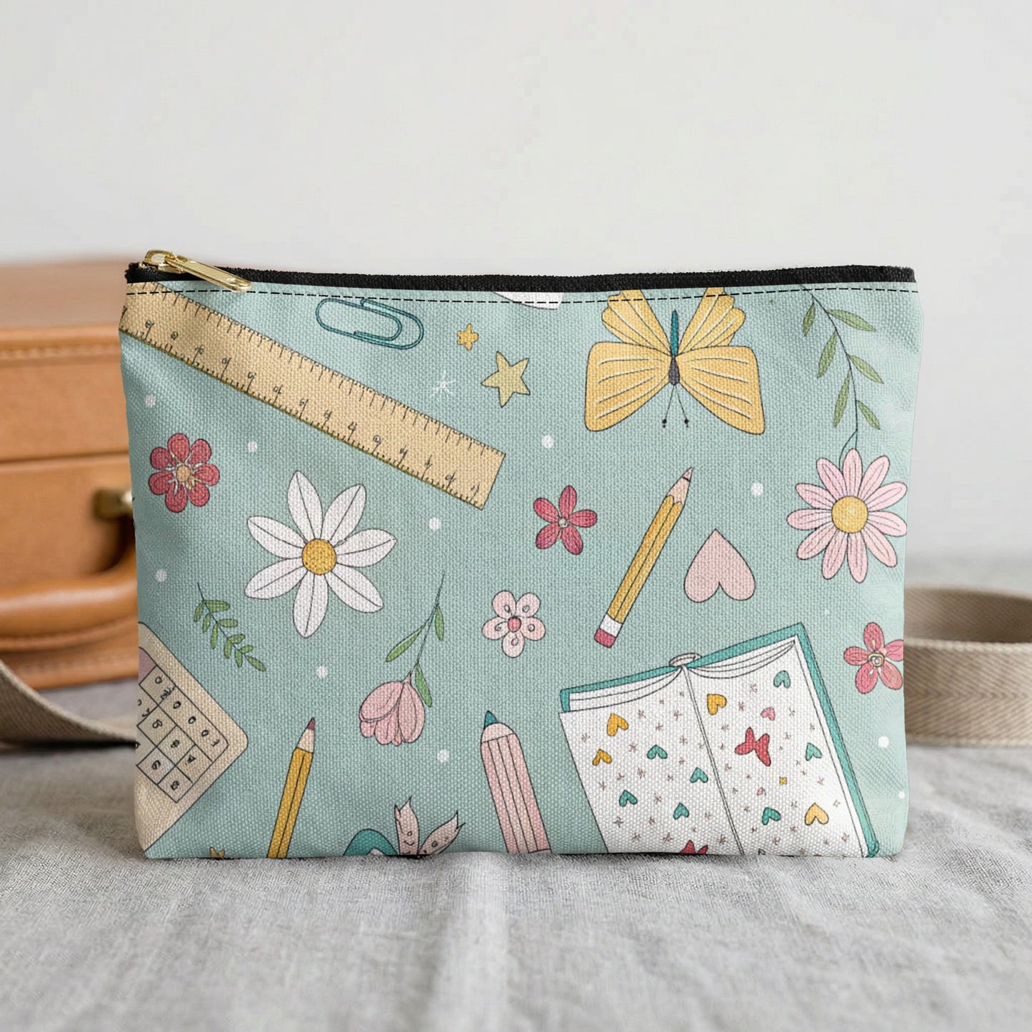 Pouch with teal background featuring a pattern of school supplies and flowers.