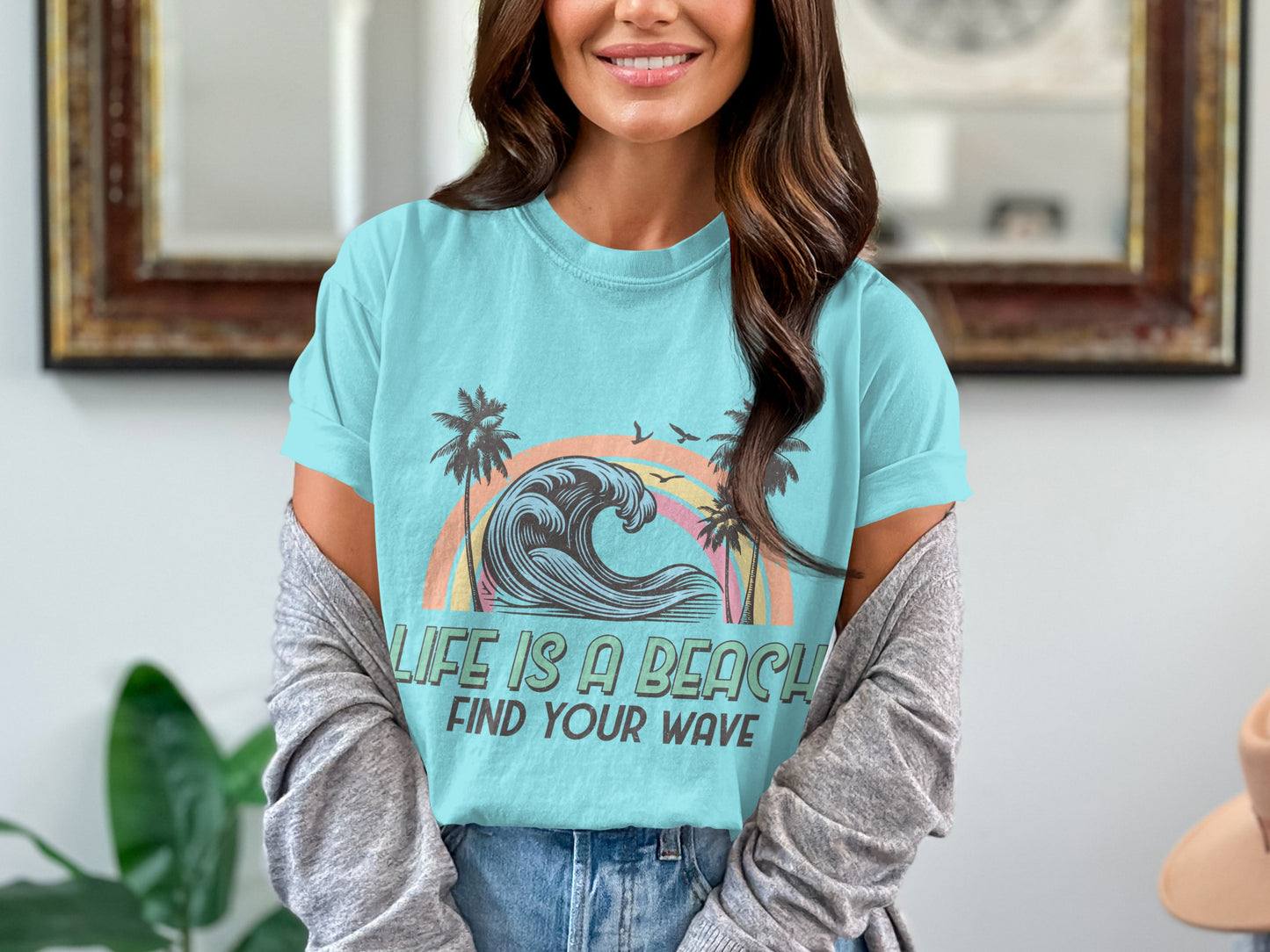 Teal t-shirt with rainbow, waves, palm trees, and text: LIFE IS A BEACH FIND YOUR WAVE.