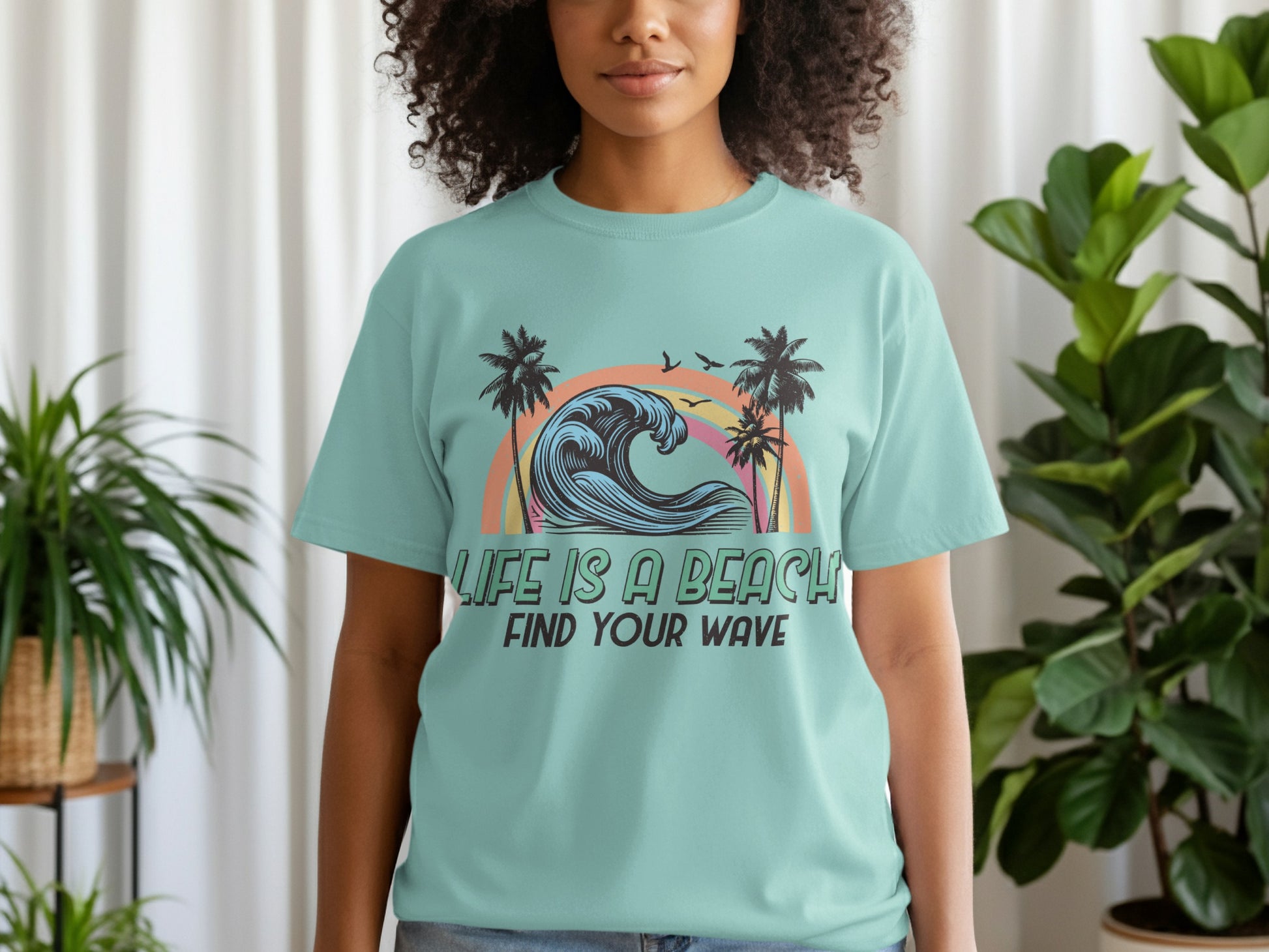 Teal t-shirt with graphic of a wave, palm trees, and text "LIFE IS A BEACH FIND YOUR WAVE".