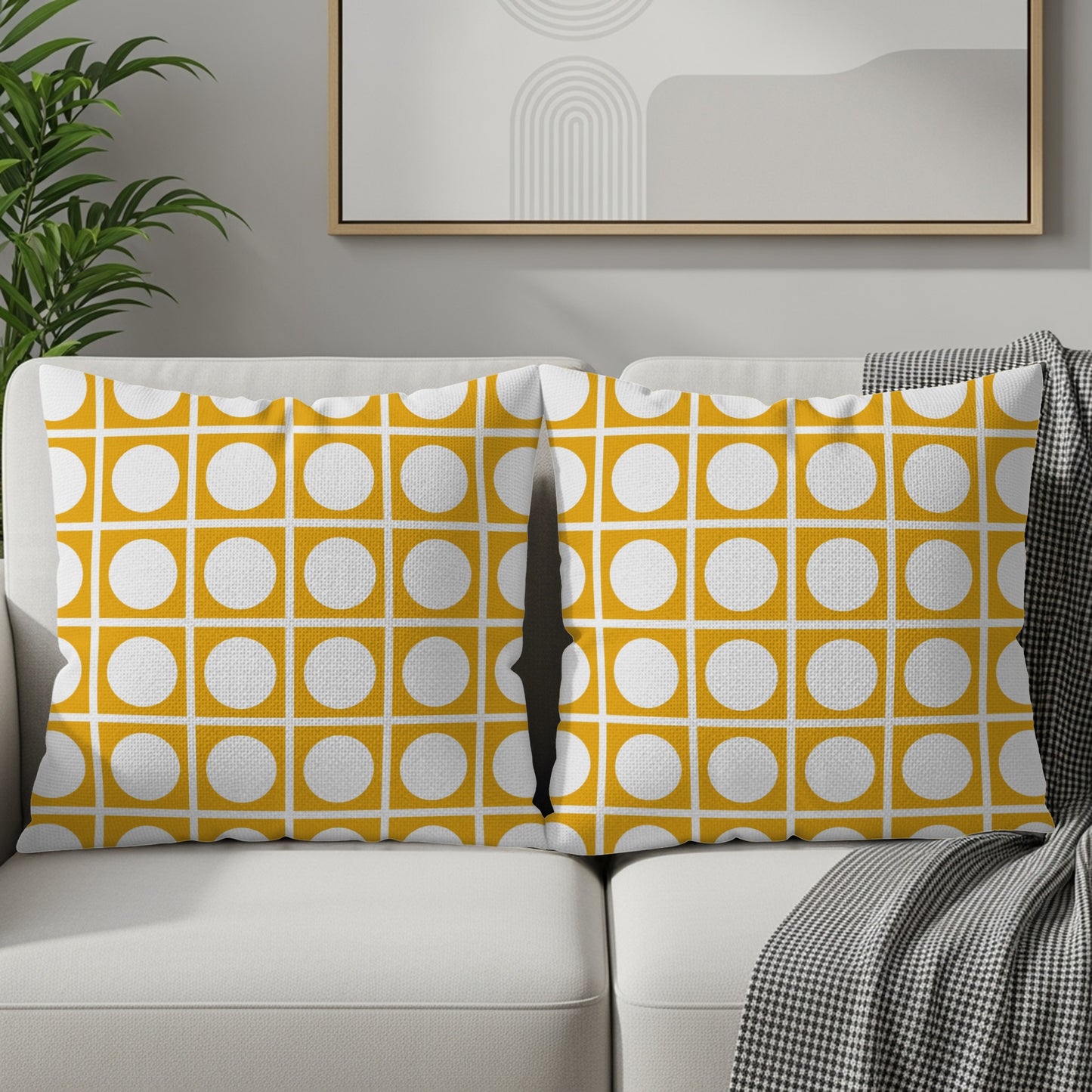 Two throw pillows with a yellow and white geometric circle grid pattern on a couch.