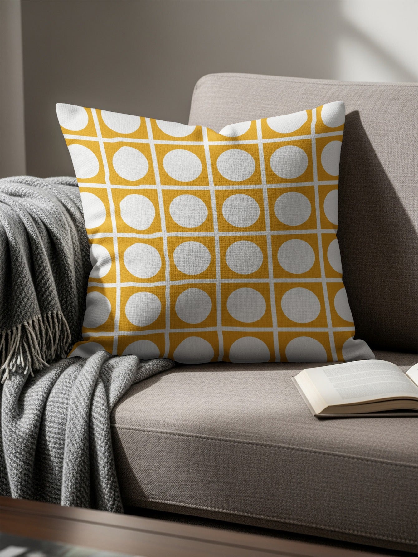 Yellow and white grid geometric pattern pillow on a couch with a draped blanket.