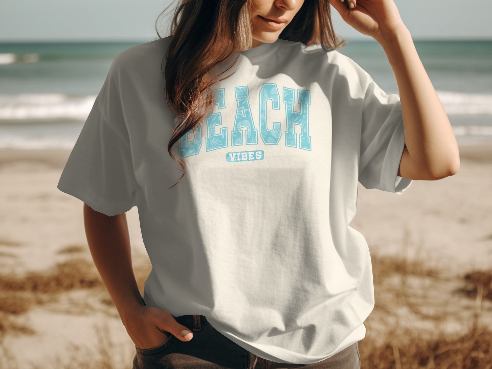 White t-shirt with "BEACH VIBES" text, worn by a person on a beach.