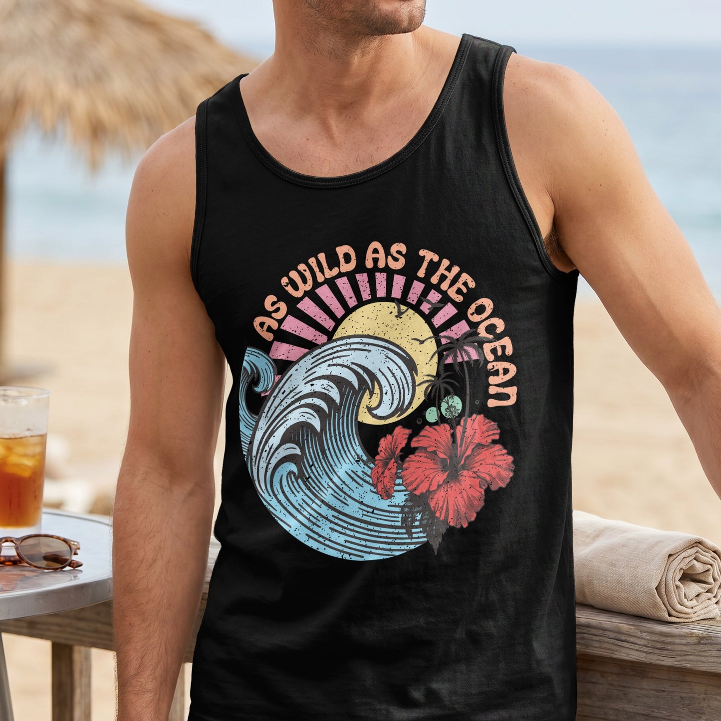 Black tank top with "As Wild As The Ocean" text, wave, sun, and hibiscus.