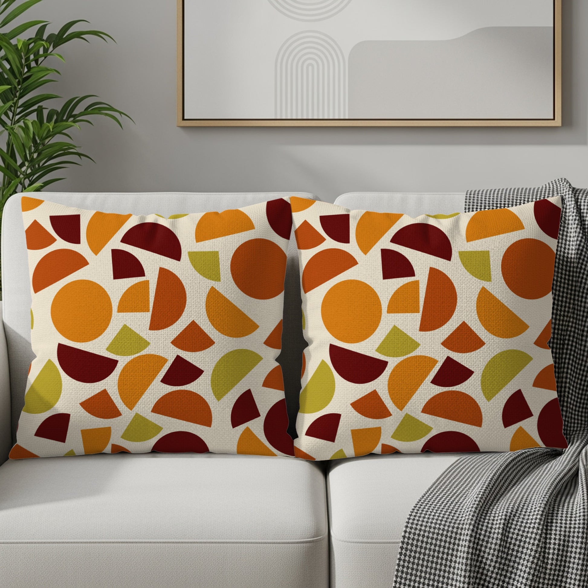 Two throw pillows with a cream background and a geometric pattern in orange, red, and green.