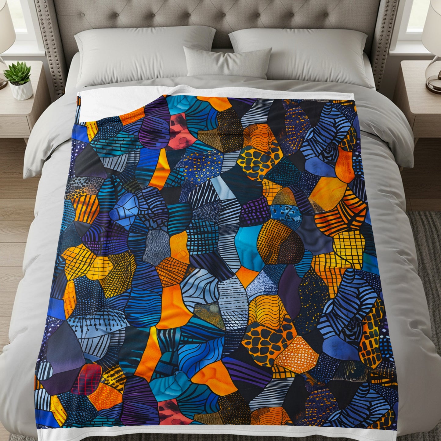 Colorful abstract patchwork blanket spread across a bed with white bedding.
