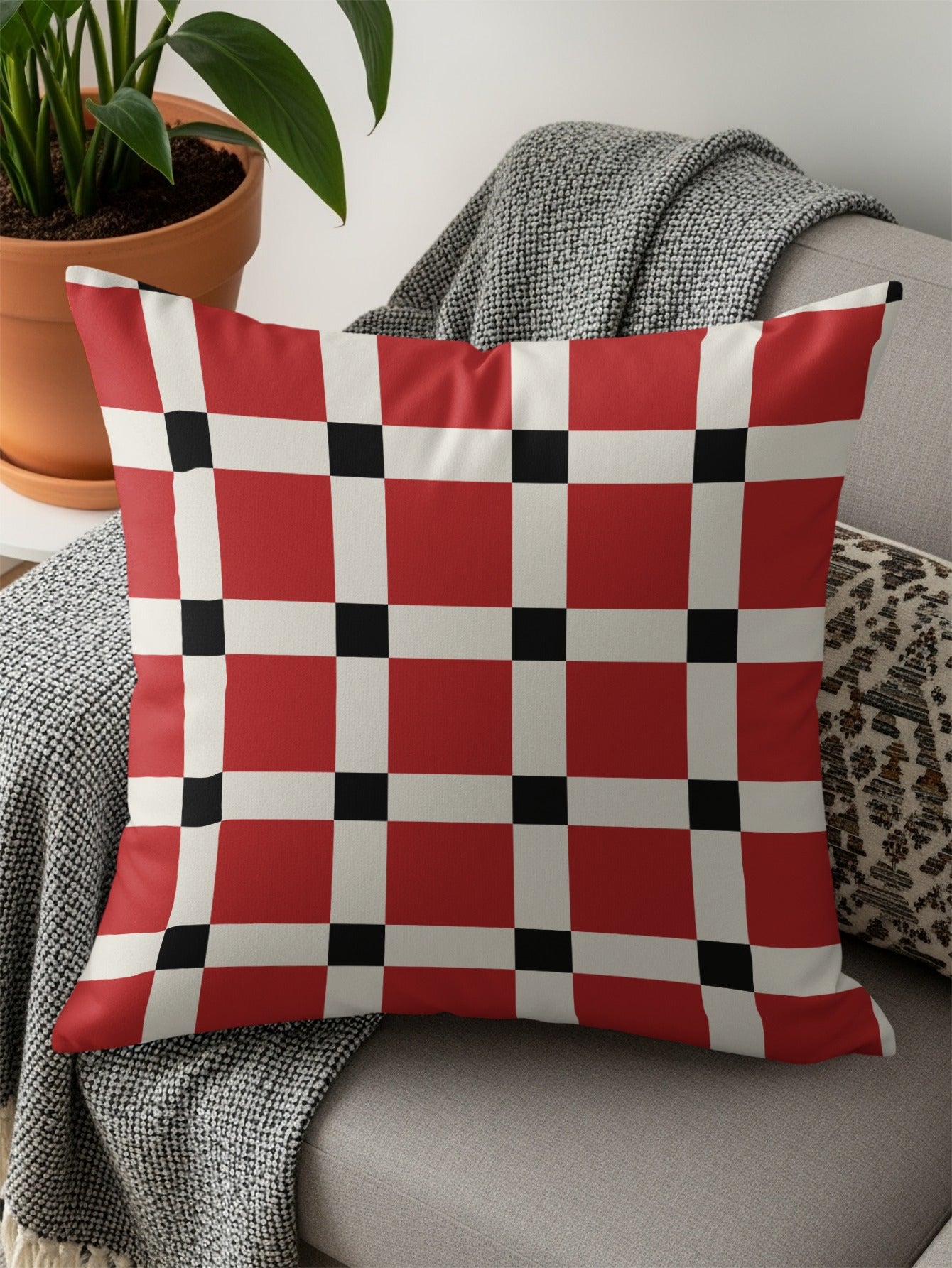 Red, white, and black checkerboard pattern throw pillow on a couch.